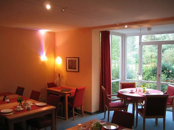 Frühstücksraum mit gedeckten Tischen und großer Fensterfront