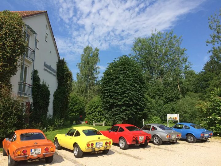 Reihe bunter Sportwagen vor dem Haus