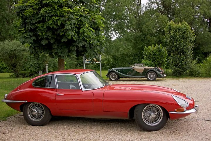 Roter Jaguar E-Type von der Seite, dahinter ein grüner Roadster