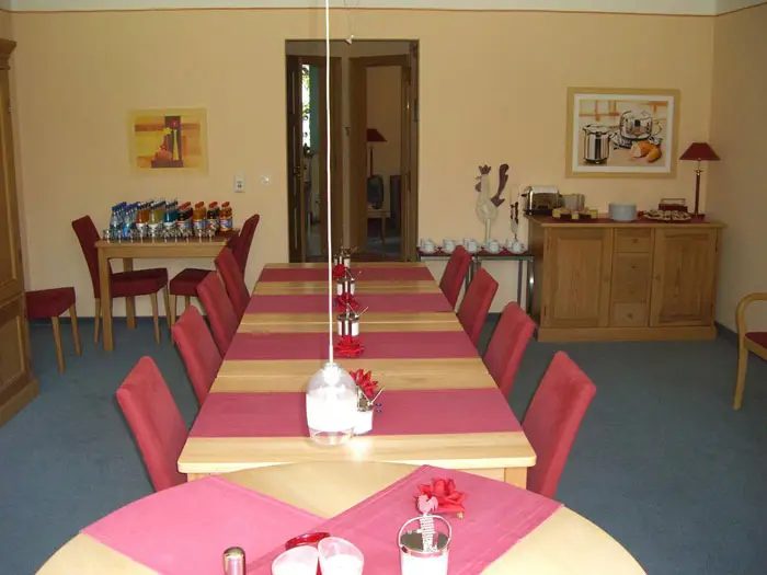 Tagungsraum mit langer Tafel und roten Stühlen