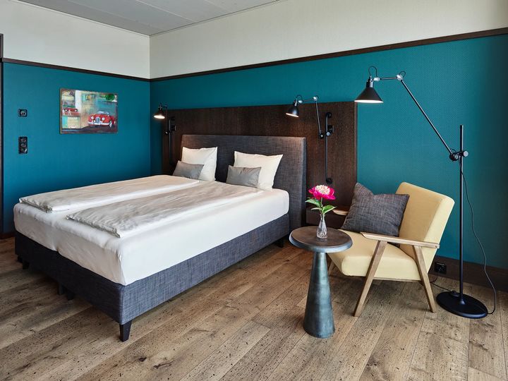 Doppelzimmer mit petrolfarbener Wand, Bett und Sessel