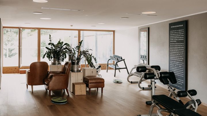 Heller Fitnessraum mit Geräten und Lounge-Sesseln