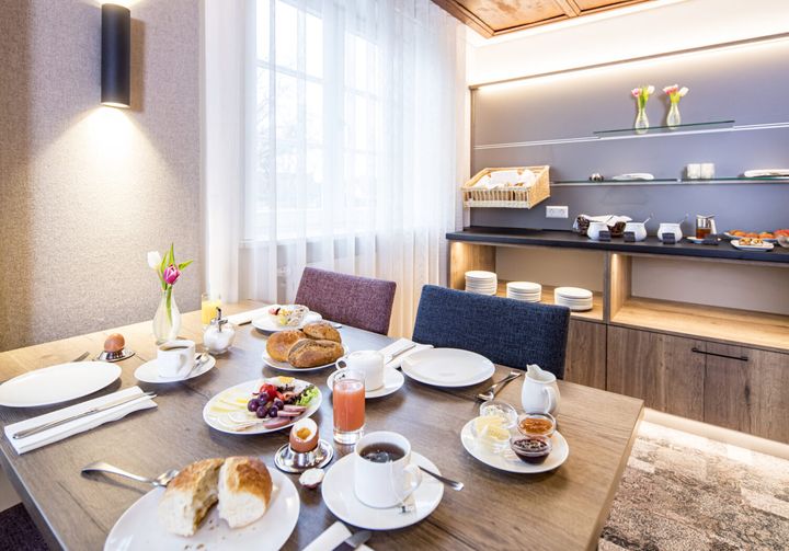 Frühstücksraum mit gedeckten Tischen und Buffet im Hintergrund