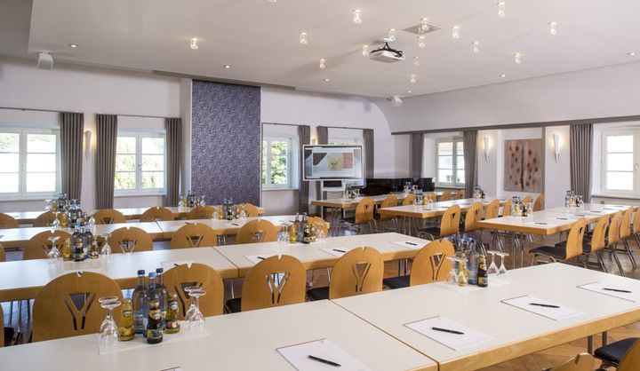 Heller Saal mit Tischreihen und Stühlen in Tagungsbestuhlung