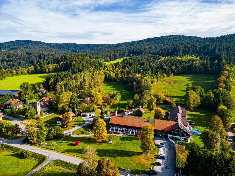 Luftaufnahme des Hotels inmitten von Wiesen und bewaldeten Hügeln