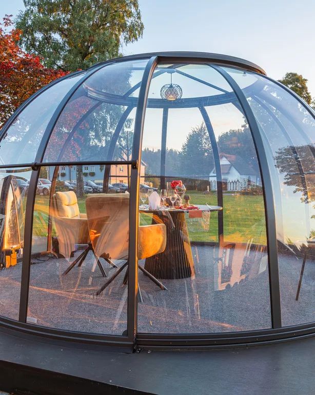 Gedeckter Tisch in einer gläsernen Kuppel mit Blick nach draußen