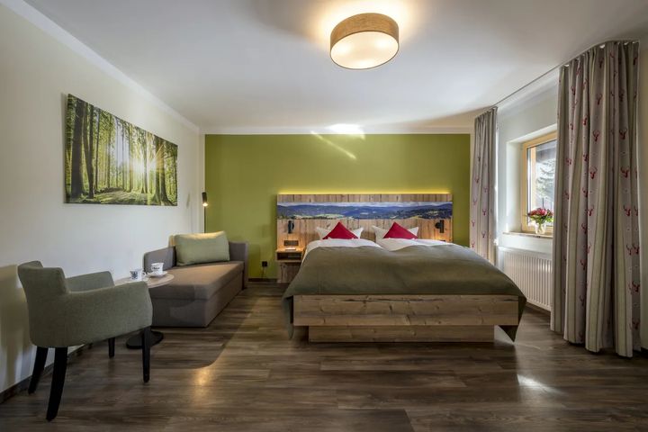 Doppelzimmer mit grüner Wand, Doppelbett und Sitzecke