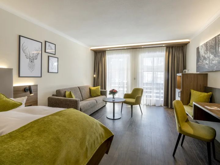 Helles Zimmer mit Bett, Sofa, Schreibtisch und Balkontür