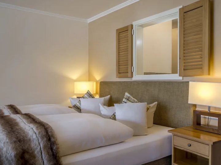 Bett mit Fellplaid, Kissen und Fensterläden an der Wand