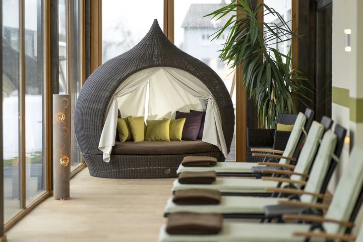 Ruhebereich mit Rattan-Liegeinsel und Liegen im Wellnessbereich