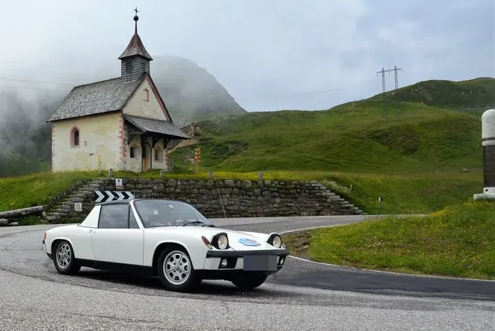 Weißer Sportwagen vor einer Kapelle in den Bergen