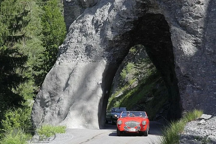 Rotes Cabrio fährt durch einen Felstunnel