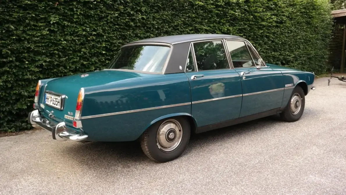 Austin Rover 3500 S V8 Baujahr 1975 zu verkaufen, Türkiser Austin Rover 3500 S V8 mit schwarzem Dach steht von der linken Seite vor einer Heckenkulisse, Chrom-Zierleiste und Stoßstangen sind sichtbar.