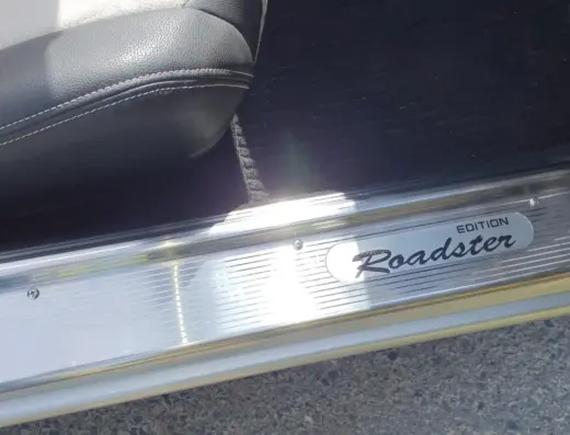 Mazda MX5 Baujahr 1990 zu verkaufen – Chromglänzende Roadster-Edition Einstiegsleiste eines Mazda MX-5 mit weißem Lederinterieur sichtbar, aufgenommen von innen des Fahrzeugs.