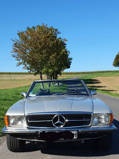 Mercedes-Benz 350 SL Baujahr 1971 zu verkaufen: Silberner Mercedes-Benz 350 SL von vorne mit offenem Verdeck auf einer Landstraße vor Bäumen und Feldern