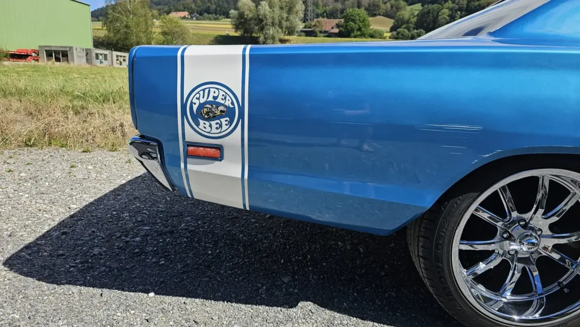 Dodge Coronet Super Bee Baujahr 1969 zu verkaufen, Hintere Seitenpartie des blauen Dodge Coronet Super Bee Coupés mit weißem Heckstreifen und Super-Bee-Emblem, verchromte Felge, Kiesplatz.