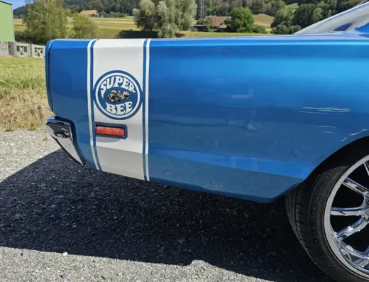 Dodge Coronet Super Bee Baujahr 1969 zu verkaufen, Hintere Seitenpartie des blauen Dodge Coronet Super Bee Coupés mit weißem Heckstreifen und Super-Bee-Emblem, verchromte Felge, Kiesplatz.