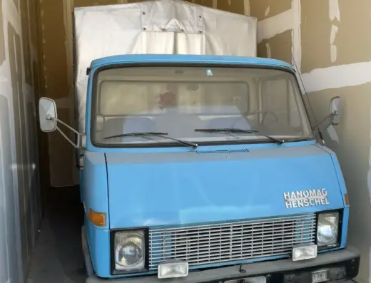 Hanomag Henschel zu verkaufen, Blauer Hanomag Henschel Lastwagen in einer Garage, Frontansicht mit charakteristischem Kühlergrill und vier Scheinwerfern.