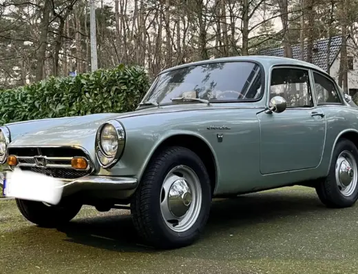 Honda S800 Baujahr 1967 zu verkaufen, Silberner Honda S800 Coupé, Dreiviertelansicht von vorn links, vor Hecke und Bäumen