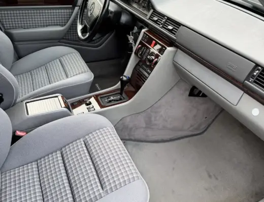 Mercedes Benz E280 Baujahr 1995 zu verkaufen – Grau-weiß karierter Innenraum einer Mercedes-Benz E280 Limousine mit Lenkrad, Armaturenbrett und Mittelkonsole, fotografiert von der Fahrerseite.