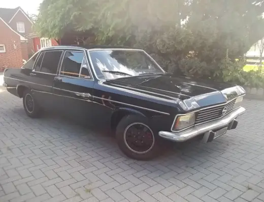 Opel Diplomat Baujahr 1977 zu verkaufen, Schwarzer Opel Diplomat von der Seite auf Pflastersteinen geparkt, glänzend poliert mit verchromten Details und dunklen Felgen.