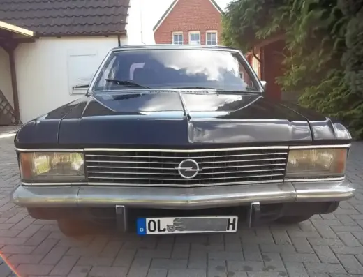 Opel Diplomat Baujahr 1977 zu verkaufen, Schwarzer Opel Diplomat der 1970er Jahre von vorne auf gepflastertem Parkplatz, mit verchromtem Grill und ausgefahrenem Scheibenwischer.