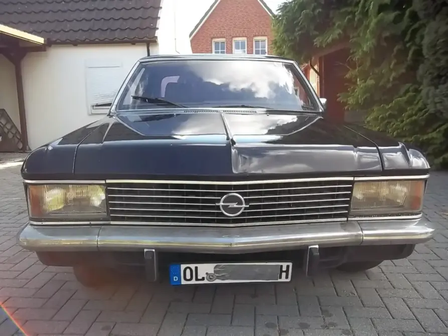 Opel Diplomat Baujahr 1977 zu verkaufen, Schwarzer Opel Diplomat der 1970er Jahre von vorne auf gepflastertem Parkplatz, mit verchromtem Grill und ausgefahrenem Scheibenwischer.