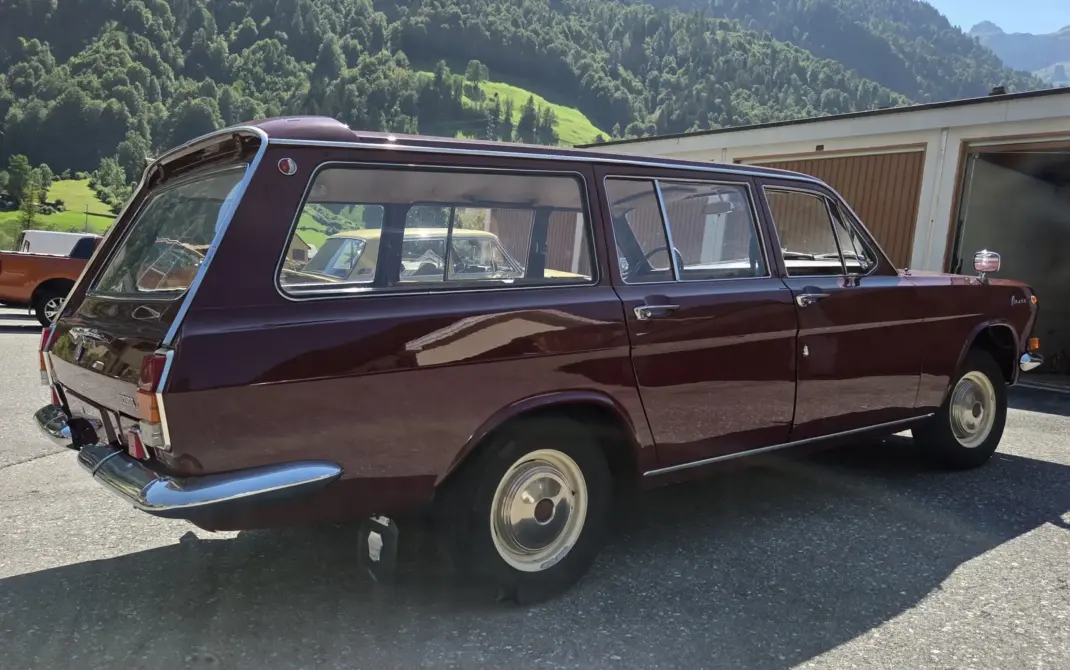Wolga GAZ 2402 zu verkaufen, Weinroter Wolga GAZ 2402 Kombi von der Seite auf einem Parkplatz vor Bergkulisse