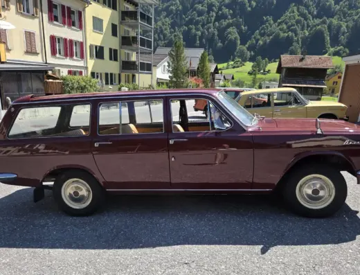 Wolga GAZ 2402 zu verkaufen, Weinroter Wolga GAZ 2402 Kombi auf einer Straße vor einem Bergdorf mit grünen Hängen