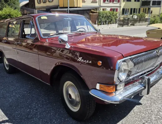 Wolga GAZ 2402 zu verkaufen, Weinroter Wolga GAZ 2402 Kombi mit verchromten Stoßstangen und hellen Felgen vor Wohnhäusern